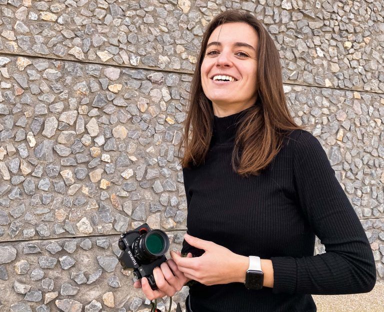 Me, a white girl with brown long hair wearing a turtleneck black t-shirt, holding a camera